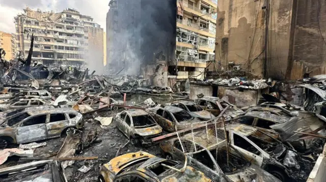 فرق الطوارئ تعمل في مواقع مستهدفة يتصاعد منها الدخان في أنحاء لبنان، وسط مشاهد لسيارات ومبانٍ مدمّرة
