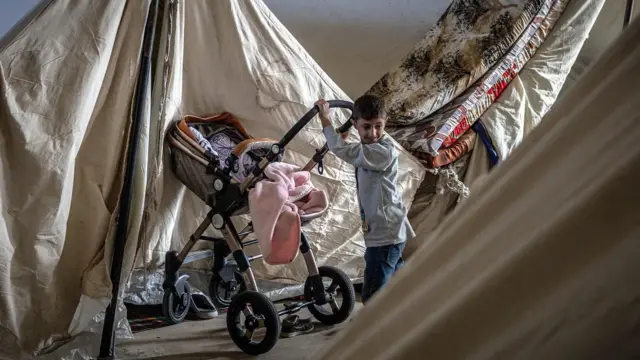 طفل نازح يدفع عربةً إلى خيمة عائلته في مخيم نزوح مؤقت